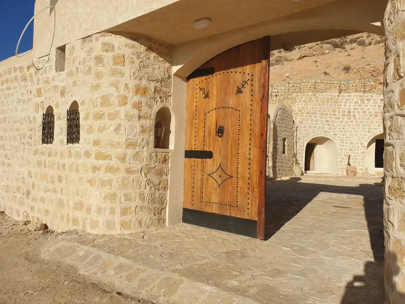 L'entrée de Dar Zmen : grande porte en bois ouverte sur le patio de pierre